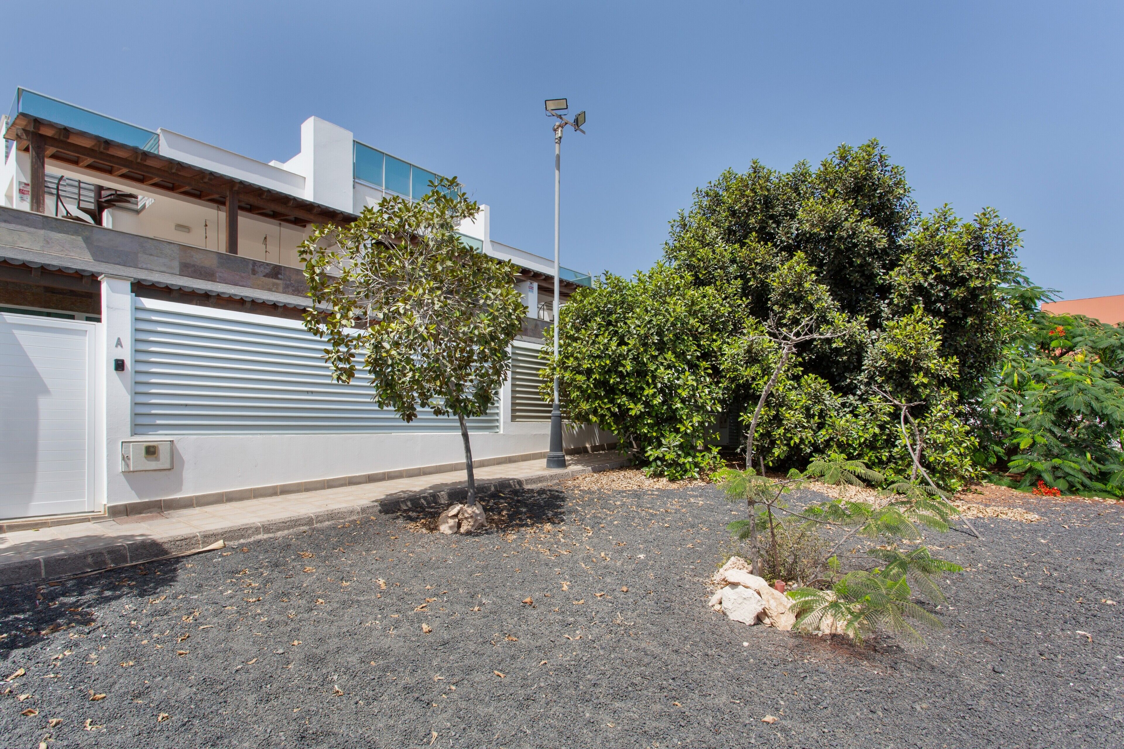 Een modern gebouw met een garage deur, een lantaarnpaal en een boom op de voorgrond.