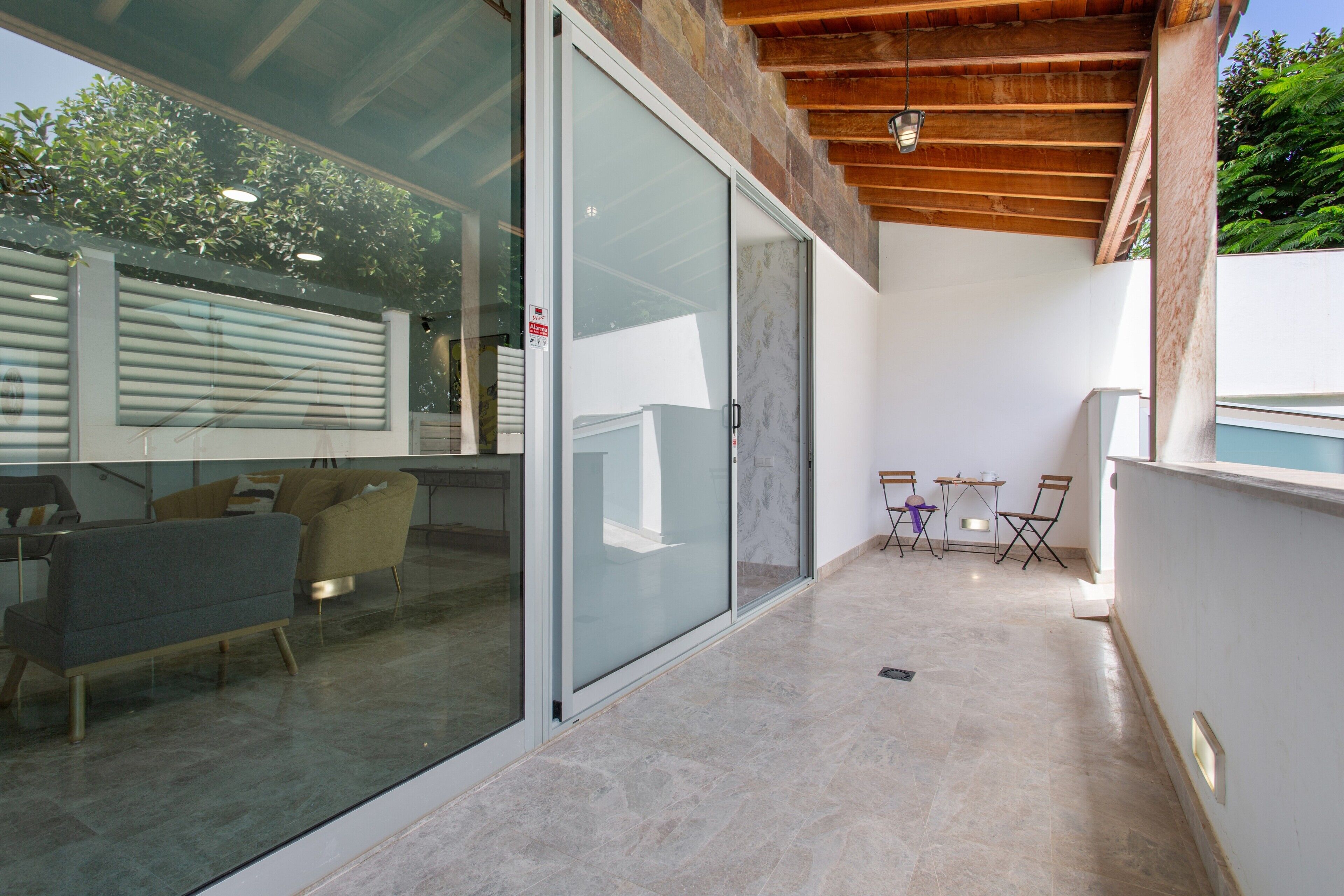 A modern interior with a glass sliding door, a wooden ceiling, and a seating area with a table and chairs.
