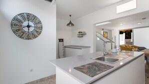 A modern kitchen with a central island, a wall clock, and a pendant light.