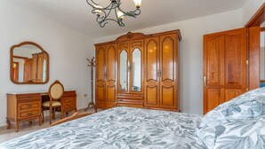 A bedroom with a large bed, wooden wardrobe, a mirror, and a chair. - 'Elikasa Mala' Holiday Apartment with Sea View, Balcony and Wi-Fi (Mala)