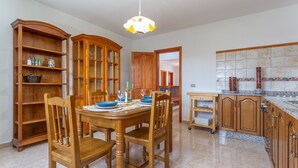 A dining area with wooden furniture, a chandelier, and a kitchen with granite countertops. - 'Elikasa Mala' Holiday Apartment with Sea View, Balcony and Wi-Fi (Mala)