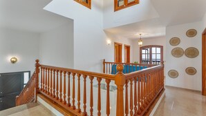 A multi-level interior with a wooden staircase, a flat-screen TV, and decorative wall plates. - 'Elikasa Mala' Holiday Apartment with Sea View, Balcony and Wi-Fi (Mala)