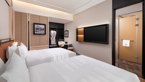 A hotel room with two beds, a TV, a wardrobe, and a bathroom door.
