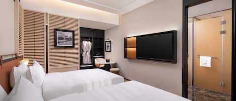 A hotel room with two beds, a TV, a wardrobe, and a bathroom door.