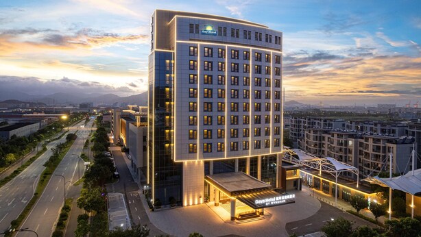 A modern hotel with a prominent Days Hotel sign, a well-lit entrance, and a view of the surrounding cityscape.