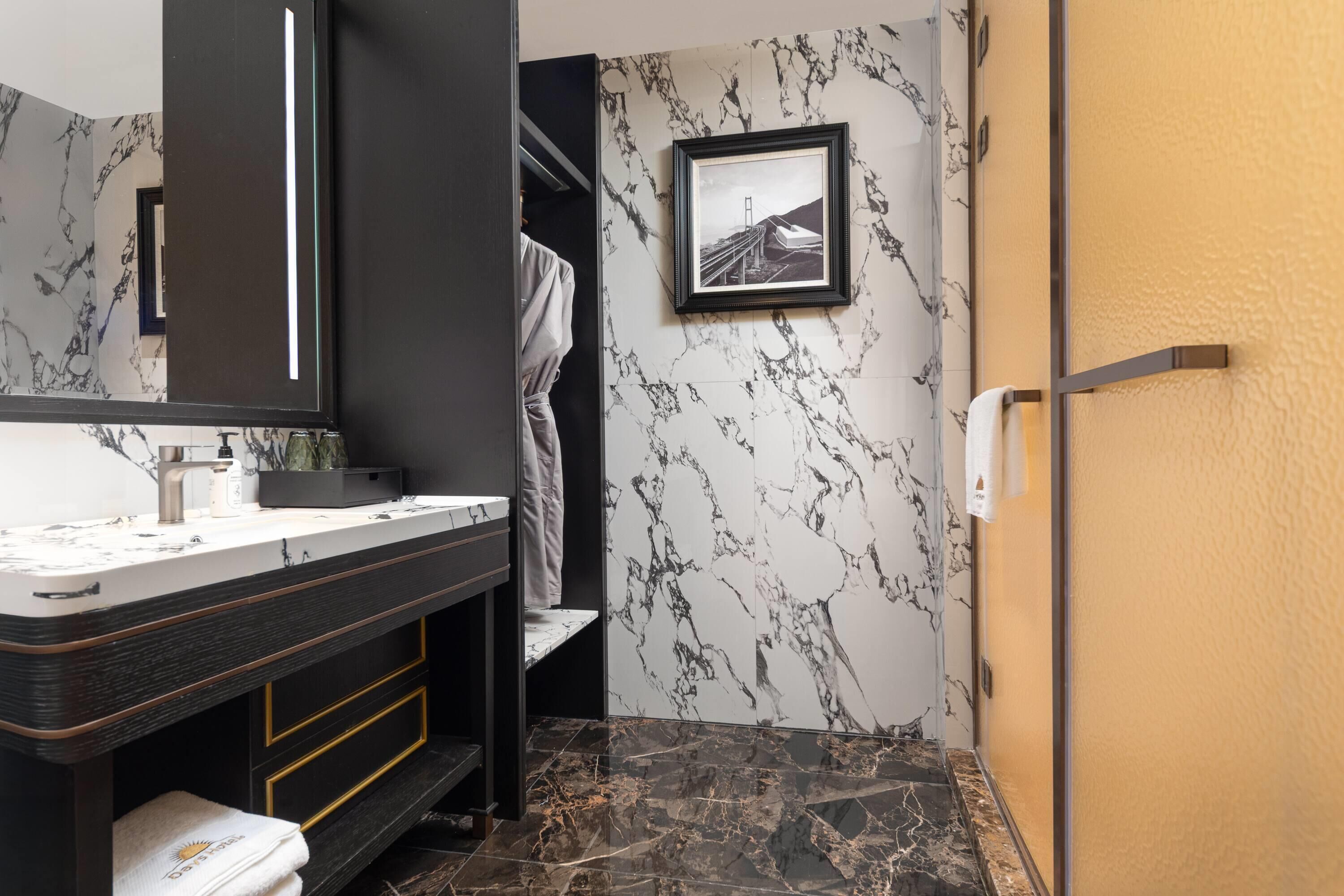 A modern bathroom with a marble vanity, a framed picture on the wall, and a towel rack.