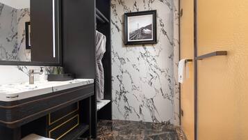 A modern bathroom with a marble vanity, a framed picture on the wall, and a towel rack.