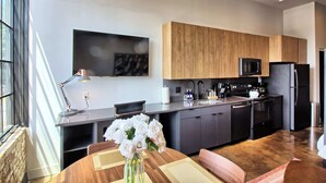 Una cocina moderna con armarios de madera, un refrigerador negro, un microondas y una cafetera.