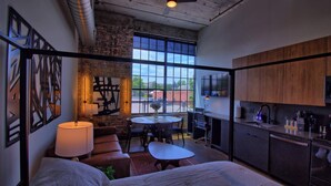 Un moderno espacio tipo loft con un gran ventanal, zona de comedor y kitchenette.