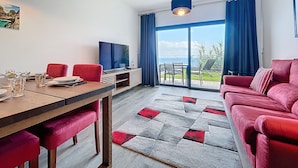 Una sala moderna con televisor, muebles rojos y un ventanal con vistas.