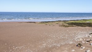 Une plage avec un ciel dégagé, une mer calme et un rivage rocheux.