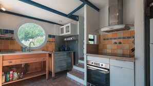 A compact kitchen with a built-in oven, a window, and a tiled backsplash.