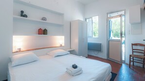 A bedroom with a bed, a wardrobe, a television, and a chair.