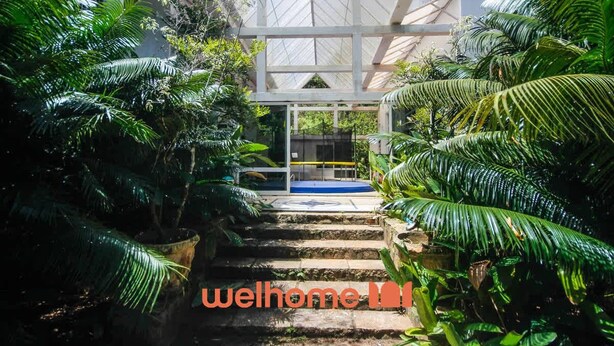 A well-maintained garden pathway leading to a building with a white facade and a glass entrance.
