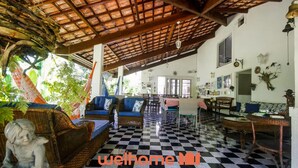 A spacious living area with a checkered floor, wicker furniture, and a ceiling with exposed beams.