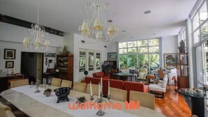 A spacious dining area with a long table, multiple chairs, and a chandelier.