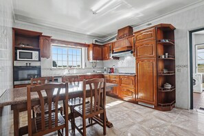 A kitchen with wooden cabinets, a microwave, a stove, and a dining table with chairs.