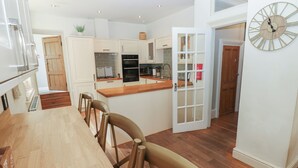A modern kitchen with white cabinetry, a wooden countertop, and a built-in oven. - Hampton House (St Bees)