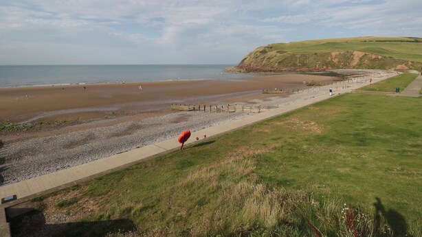A coastal landscape with a sandy beach, grassy areas, and a clear sky. - Hampton House (St Bees)