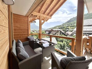 A balcony with wicker furniture and a table, overlooking a mountainous landscape. - 200m from resort center, 5th floor, view mountain, terrace, tv, ski locker, 89m², Serre Chevalier (Briançon)