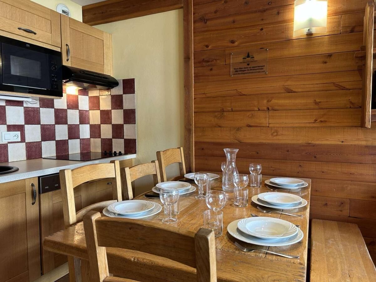 A wooden dining table set with plates, glasses, and cutlery.
