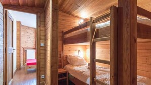 Una baita in legno con letti a castello, un tavolino e un termosifone.
