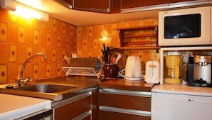 A kitchen with a sink, stove, microwave, and coffee maker. - 100m from ski slopes, 1st floor, view village, balcony, tv, 26m², Le Grand Bornand (Le Grand-Bornand)