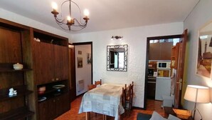 A dining area with a table and chairs, a chandelier, a mirror, and a sofa with a lamp. - 100m from ski slopes, 1st floor, view village, balcony, tv, 26m², Le Grand Bornand (Le Grand-Bornand)