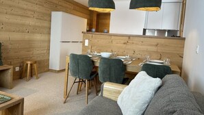 Una cucina moderna con pareti in legno, un'area pranzo con tavolo e sedie e un angolo soggiorno accogliente con divano.