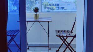 Een balkon met een tafel, een stoel en een bloempot.