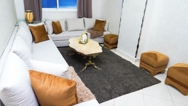 Een moderne woonkamer met een witte bank, een marmeren salontafel en een donkergrijs vloerkleed.