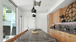 Une cuisine moderne avec un plan de travail en marbre, des armoires en bois et une grande horloge.