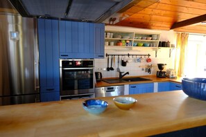 Una cocina con armarios azules, electrodomésticos de acero inoxidable y encimera de madera.