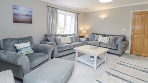 A living room with two grey sofas, a coffee table, and a rug. - Woodlark (King's Lynn)