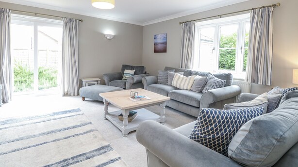 A spacious living room with a grey sofa set, a coffee table, and a lamp. - Woodlark (King's Lynn)