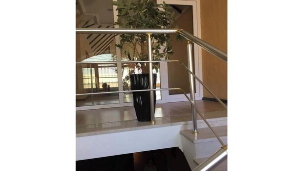 Un escalier avec une rampe en verre et un pot de fleurs placé sur le palier.
