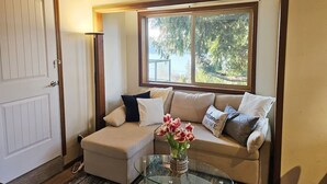 A cozy living room with a sofa, a glass coffee table, and a vase of flowers. - Private & Serene 2BR with Amazing Lake Sammamish Views (Sammamish)