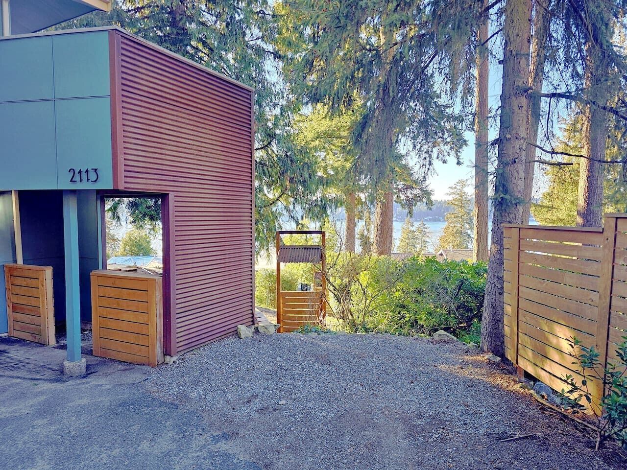 A building with a number 2113, a gravel driveway, and a wooden gate.