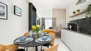A modern kitchen with a black countertop, white cabinets, and a hanging pendant light.