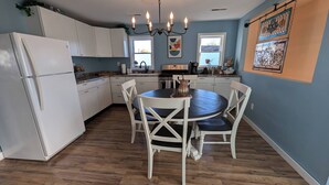 A kitchen with white cabinets, a round dining table, and a chandelier.