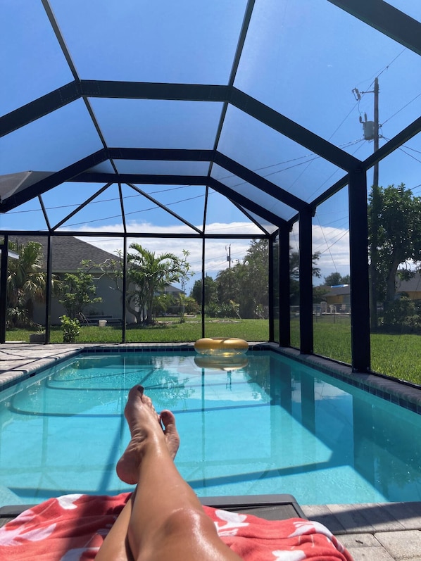 Área de piscina com estrutura coberta, céu azul límpido e vista para um bairro residencial.
