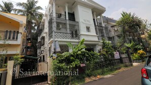 A multi-story residential building with balconies, a gated entrance, and surrounding greenery. - Sai International (Bidhannagar)