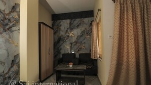 A room with a marble wall, a sofa, a wooden cabinet, and a patterned curtain. - Sai International (Bidhannagar)