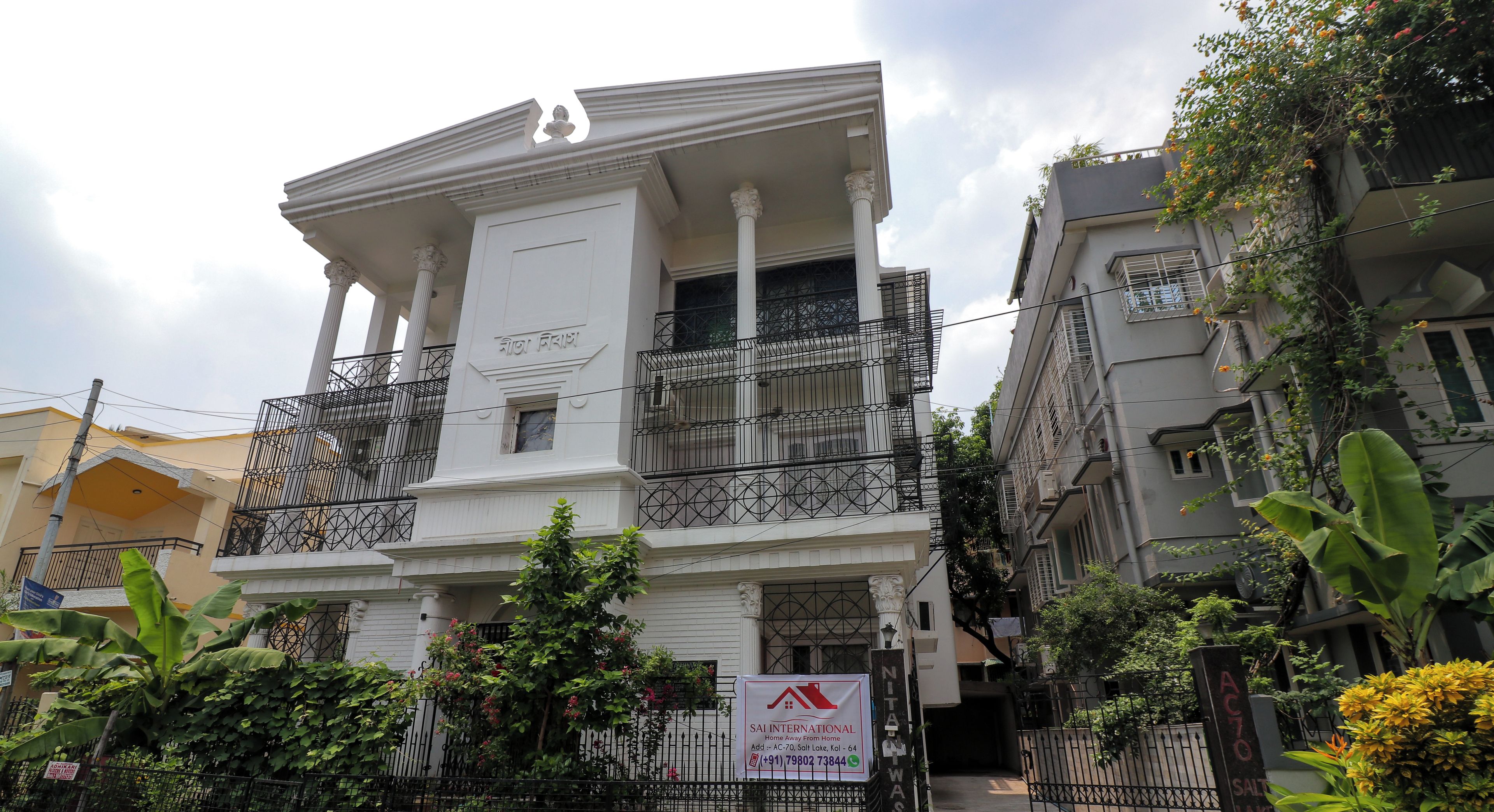 A multi-story building with a balcony, a signboard, and a gated entrance.
