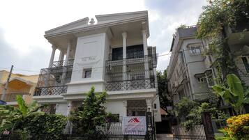 A multi-story building with a balcony, a signboard, and a gated entrance.