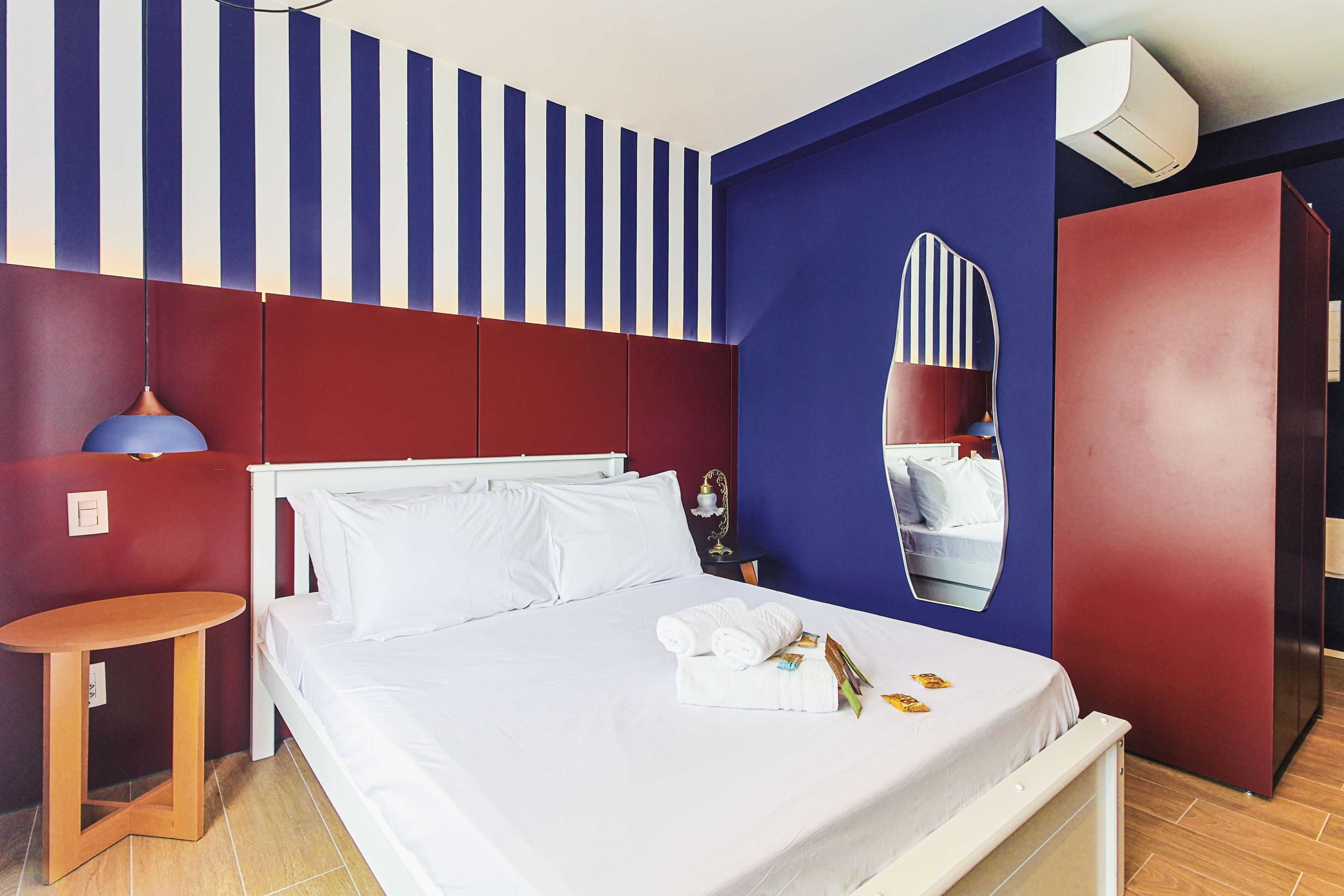 A hotel room with a bed, a small table, a mirror, and a wardrobe.