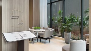 A modern interior with a sign indicating a coworking space, lounge, and delivery area. - Lira Perdizes (Sao Paulo)