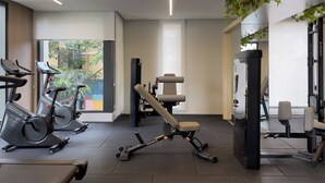 A modern gym with stationary bikes, a bench press, and weight machines. - Lira Perdizes (Sao Paulo)