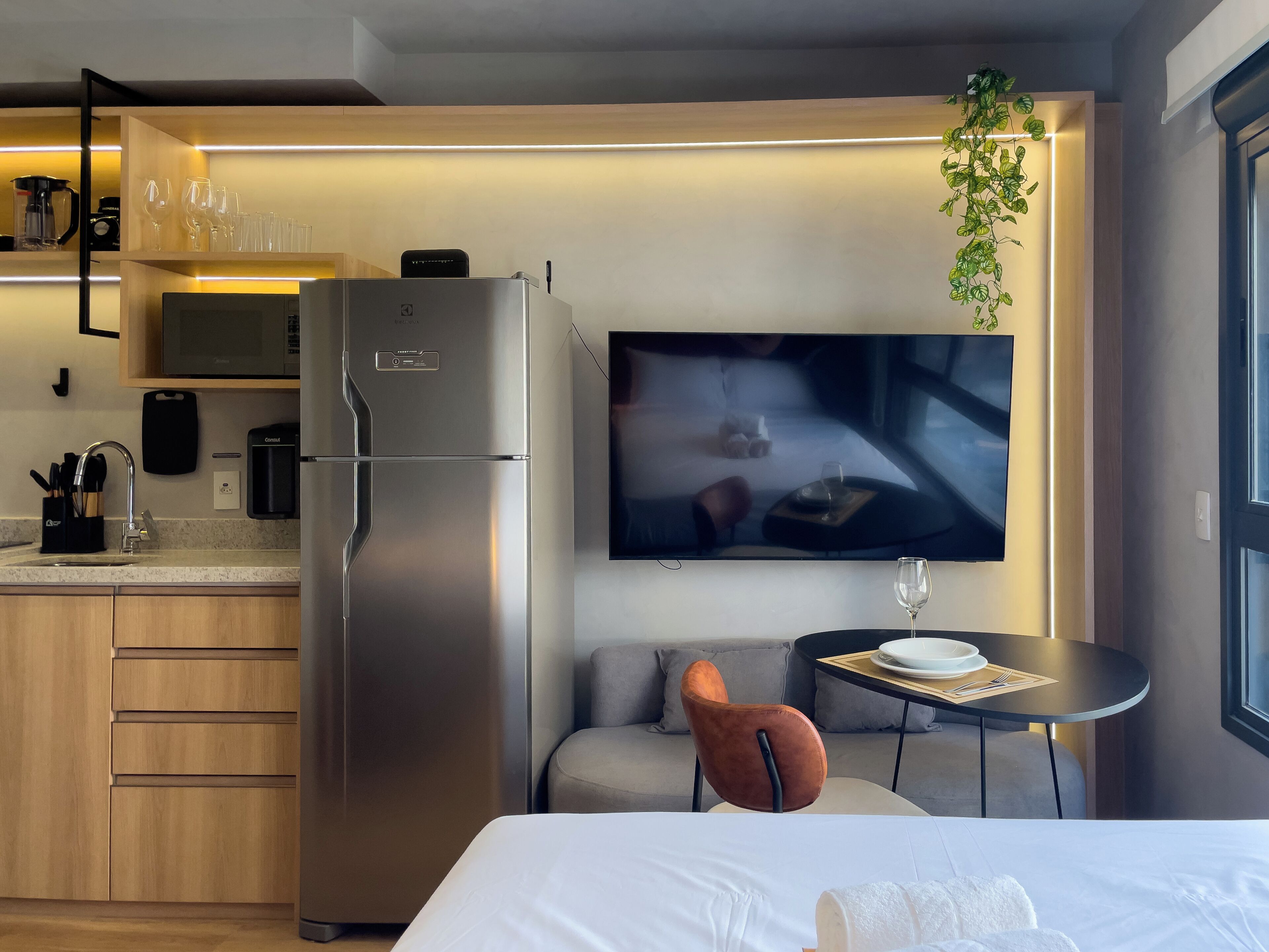 Une chambre d’hôtel moderne dotée d’une kitchenette, d’un téléviseur à écran plat, d’une table à manger et d’un canapé.