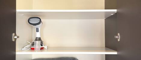 A closet with three shelves, a hairdryer, and a towel.